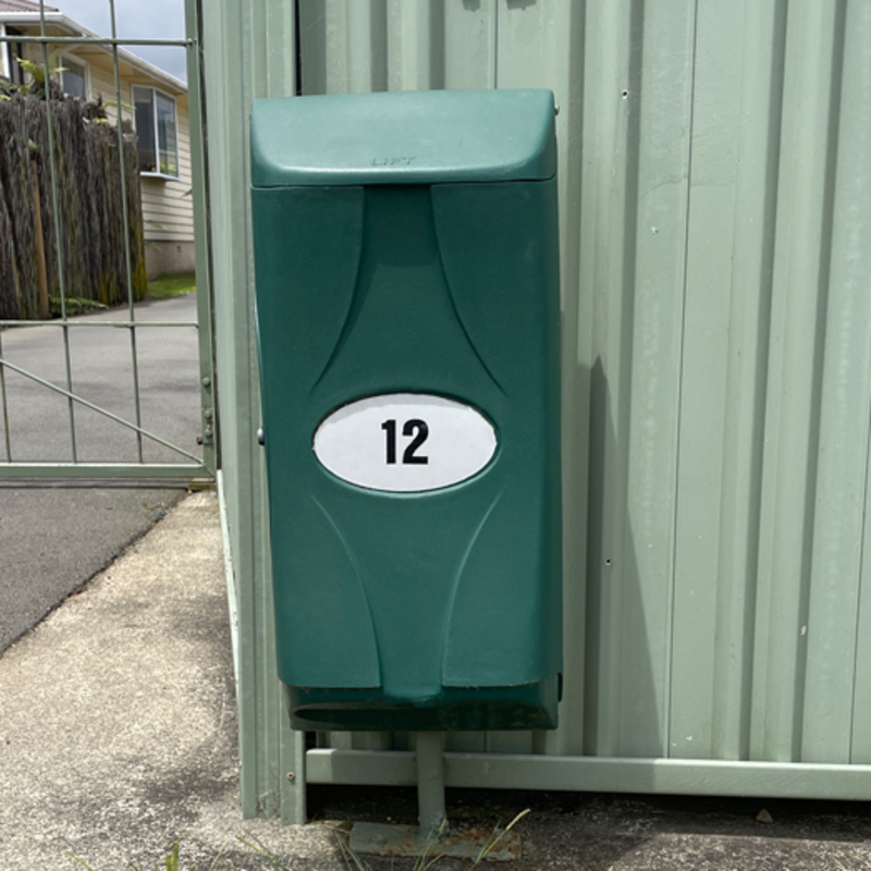 Large green letterbox on a fence